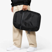 Sac à dos ordinateur Le Quotidien noir, porté à la main par sa poignée
